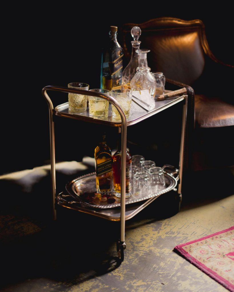 A luxury whiskey bar cart with decanters and glassware in a sophisticated setting.