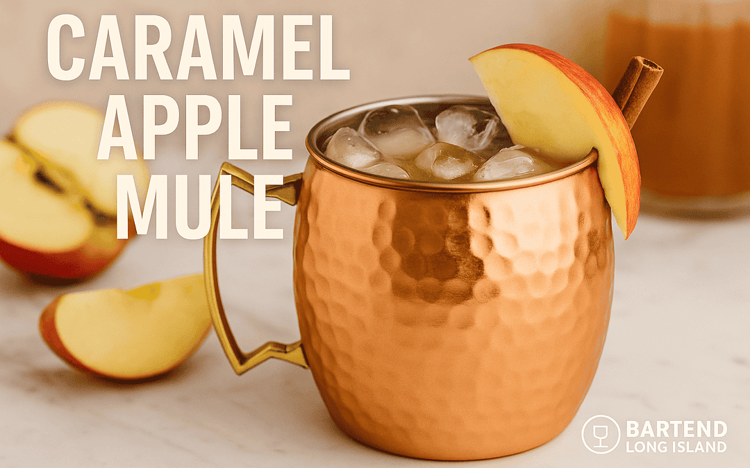Caramel Apple Mule cocktail in a copper mule mug with ice cubes, apple slice, and cinnamon stick garnish on a marble bar top with blurred autumn background. Text overlay reads Caramel Apple Mule with Bartend Long Island logo