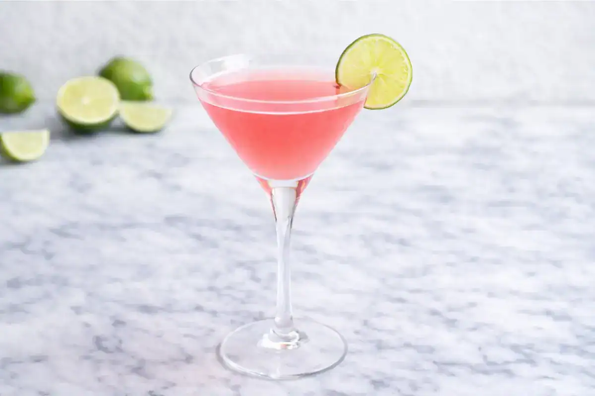 Pink cosmopolitan cocktail in a chilled martini glass with a citrus twist on a bright background
