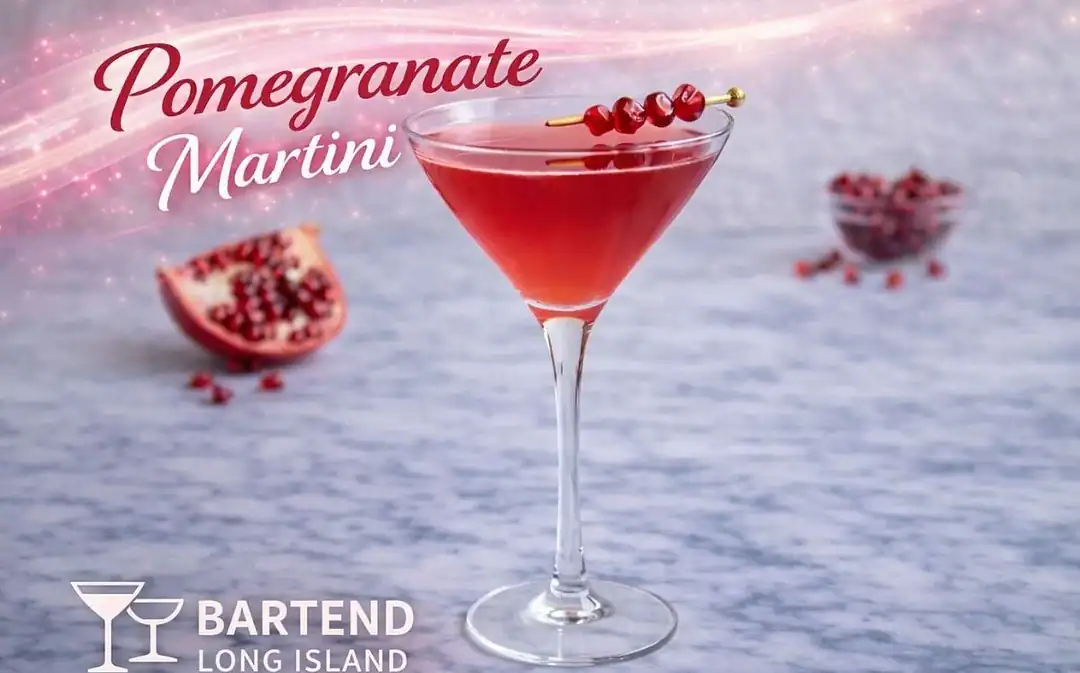 pomegranate cocktial in martini glass garnished with three pomegranates on a skewer