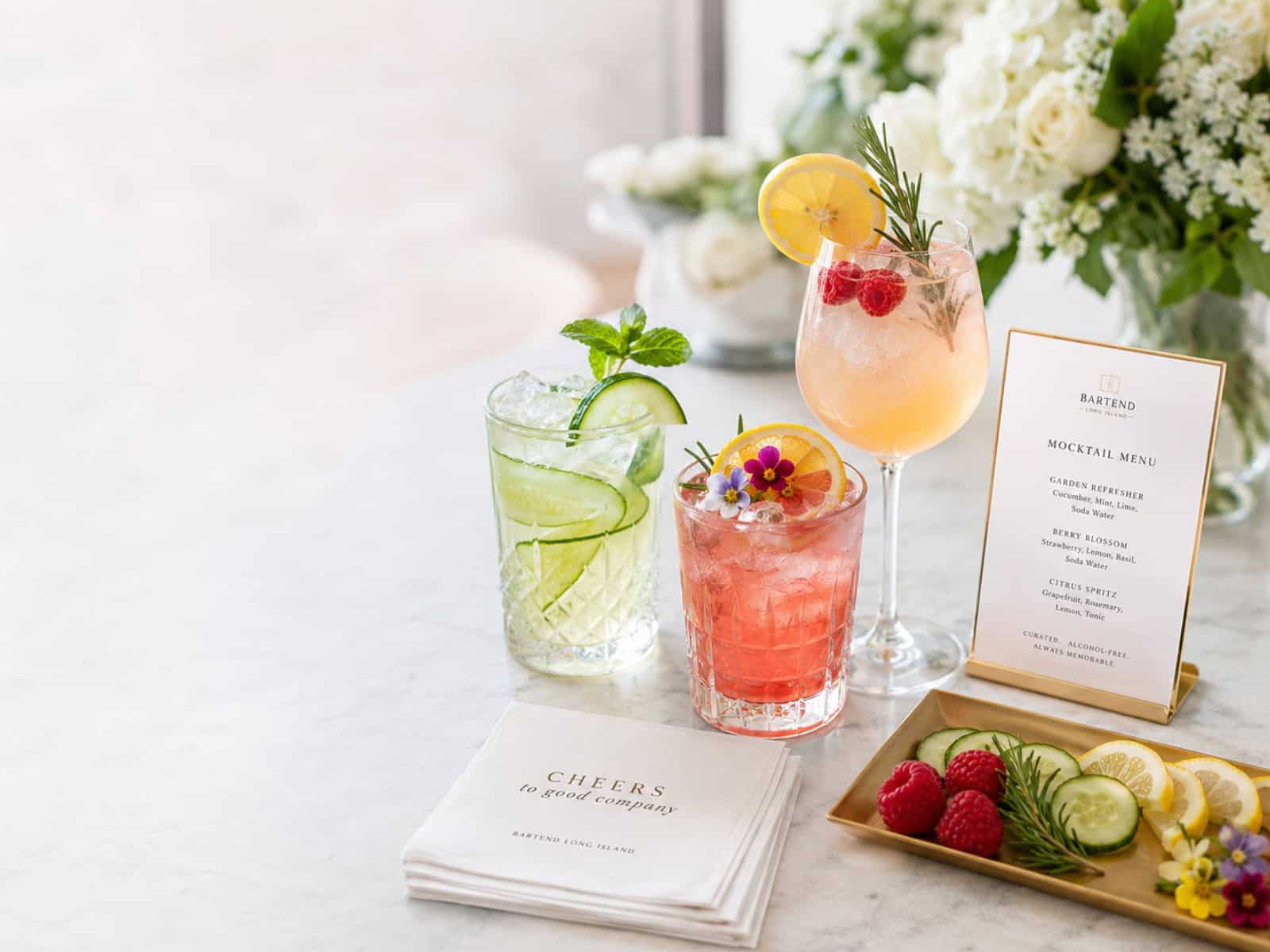 A polished private event mocktail setup with colorful alcohol-free drinks, fresh garnishes, citrus, herbs, and elegant glassware.